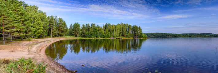 A wide panorama of a beautiful forest lake in Finland. Traditional Finnish nature, beautiful summer landscape.