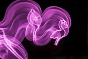 Neon pink flamingo LED lamp in motion as blurred abstract background on black.