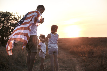 A happy family with an American flag at sunset.