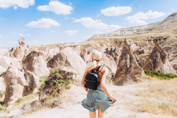 Naklejka premium A blonde girl runs across the mountains in Turkey in Cappadocia. Follow me.
