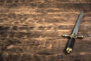 Pirate dagger on a brown wooden table background with copy space.