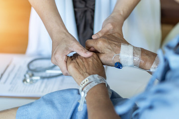 Elderly senior aged patient on bed with geriatric doctor holding hands for trust and nursing health care, medical treatment, caregiver and in-patient ward healthcare in hospital