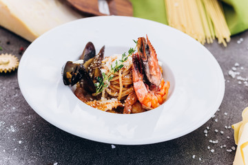 Pasta with king prawns on a gray background in a white dish.