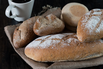 Many kind of bread put on handmade cloth on wooden table,prepare serve for breakfast or another meal.