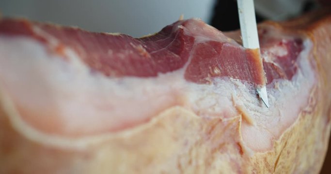 Womans hand cutting and slicing jamon , Close up slow motion shot . Hamon .