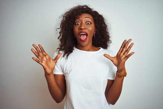 Young african american woman wearing t-shirt standing over isolated white background celebrating crazy and amazed for success with arms raised and open eyes screaming excited. Winner concept