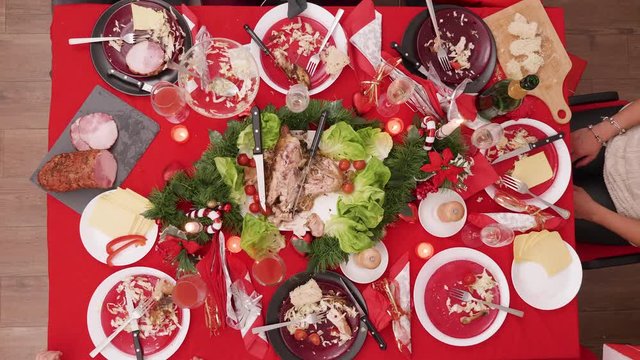 Top view of girl giving gift box over the christmas table with traditional food.