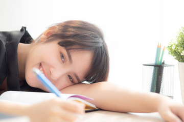 Beautiful portrait young asian woman smile and happy writing learning exam or homework and lying with desk, lifestyle beauty asia girl with work, education and business concept.