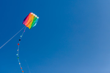 Brightly colored kite in the wind on a blue sky without clouds.Feel freedom.