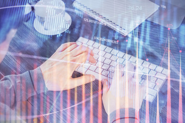 Multi exposure of graph with man typing on computer in office on background. Concept of hard work.