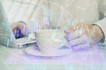 Double exposure of graph with man typing on computer in office on background. Concept of hard work.