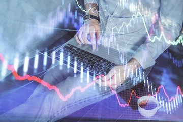 Forex graph with businessman working on computer in office on background. Concept of analysis. Double exposure.