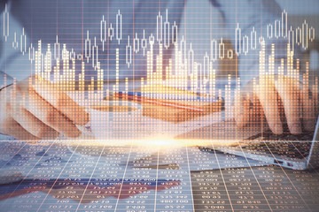 Forex graph with businessman working on computer in office on background. Concept of hardworking. Double exposure.