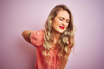 Young beautiful woman wearing t-shirt standing over pink isolated background Suffering of backache, touching back with hand, muscular pain