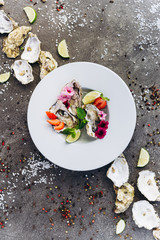 Oysters on a dish decorated with flowers on a gray background. Aphrodisiacs. 
