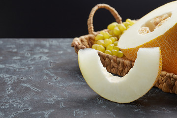 One sliced melon, on a tray of fruit on a dark background. Free space for text.