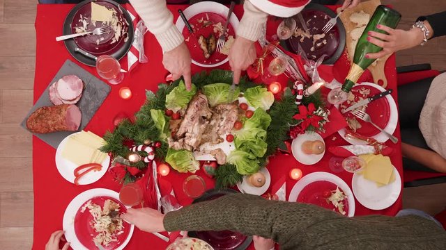 Top view of father slicing turkey for family members at christmas celebration.