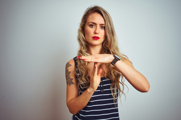 Young beautiful woman wearing stripes t-shirt standing over white isolated background Doing time...