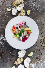 Oysters on a dish decorated with flowers on a gray background. Aphrodisiacs. 