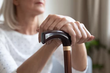 Foto op Canvas Mature woman holding hands on cane close up, sitting alone © fizkes
