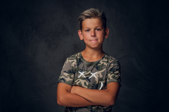 Little charming boy with nice hairstyle is posing over dark background at photo studio.