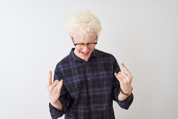 Young albino blond man wearing casual shirt and glasses over isolated white background shouting with crazy expression doing rock symbol with hands up. Music star. Heavy concept.