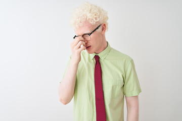 Young albino businessman wearing shirt and tie standing over isolated white background tired rubbing nose and eyes feeling fatigue and headache. Stress and frustration concept.