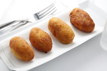 Gourmet croquetas  sobre bandeja con cubiertos. Gourmet croquettes on tray with cutlery.