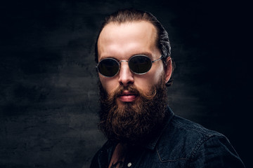 Fototapeta premium Portrait of brutal bearded man in sunglasses at dark photo studio.