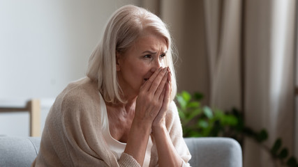 Upset mature woman crying, sitting alone, feeling lonely and unwell
