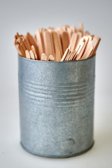 wooden stirrers in tin container on white background