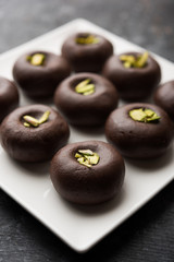Chocolate Milk peda or pera or pedha made using sweet condensed Milk and cocoa powder, garnished with Pistachio. selective focus
