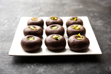 Chocolate Milk peda or pera or pedha made using sweet condensed Milk and cocoa powder, garnished with Pistachio. selective focus