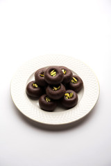 Chocolate Milk peda or pera or pedha made using sweet condensed Milk and cocoa powder, garnished with Pistachio. selective focus