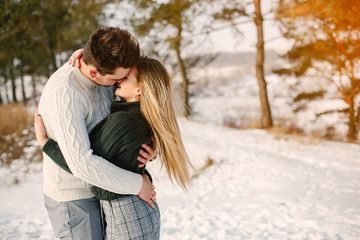 Fototapeta premium happy couple kissing and hugging in the park on a snowy winter day