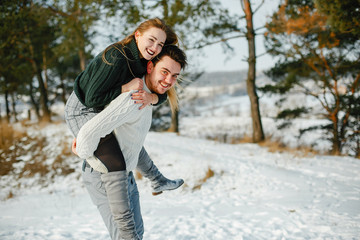 Obraz premium happy couple kissing and hugging in the park on a snowy winter day