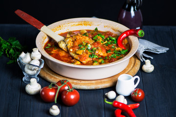 fillet of sea fish in tomato mushroom sauce with spices on a dark wooden background