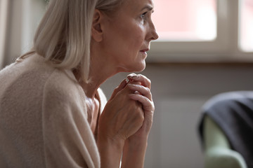 Lonely mature woman sitting alone, lost in thoughts close up