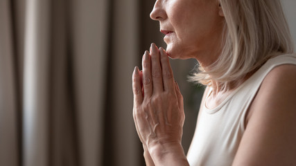 Close up mature woman puts hands in prayer with hope