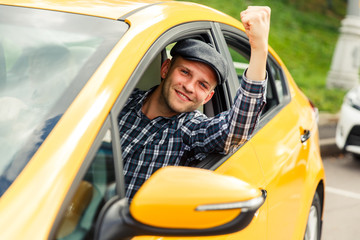 Photo of happy driver in plaid shirt sitting in yellow taxi on summer.