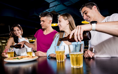 Cheerful friends in the pub. Drinking beer, wine and whisky, talking, having fun.