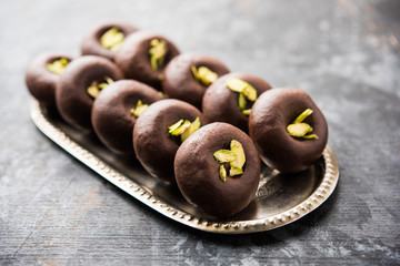 Chocolate Milk peda or pera or pedha made using sweet condensed Milk and cocoa powder, garnished with Pistachio. selective focus