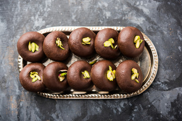 Chocolate Milk peda or pera or pedha made using sweet condensed Milk and cocoa powder, garnished with Pistachio. selective focus
