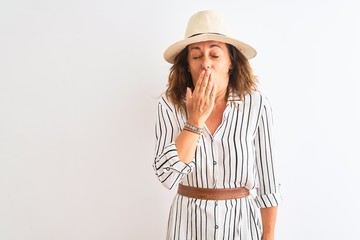 Middle age businesswoman wearing striped dress and hat over isolated white background bored yawning tired covering mouth with hand. Restless and sleepiness.