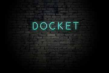 Highlighted brick wall with neon inscription docket