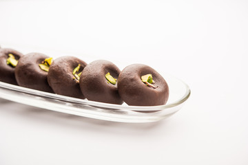 Chocolate Milk peda or pera or pedha made using sweet condensed Milk and cocoa powder, garnished with Pistachio. selective focus
