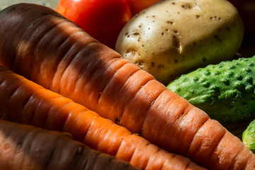 Close up image of various vegetables on old wooden background. Cucumbers, tomatoes, carrots, and potatoes