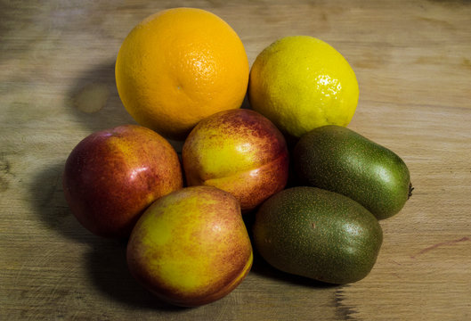 Close up image of various fruit on wooden background. peaches, lemon, orange and kiwis