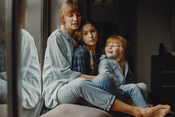 Beautiful mother with two daughters. Family sitting in the room near window