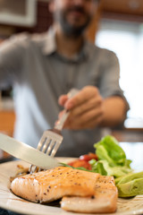 Close up of a man cutting a piece of fresh salmon grilled fillet